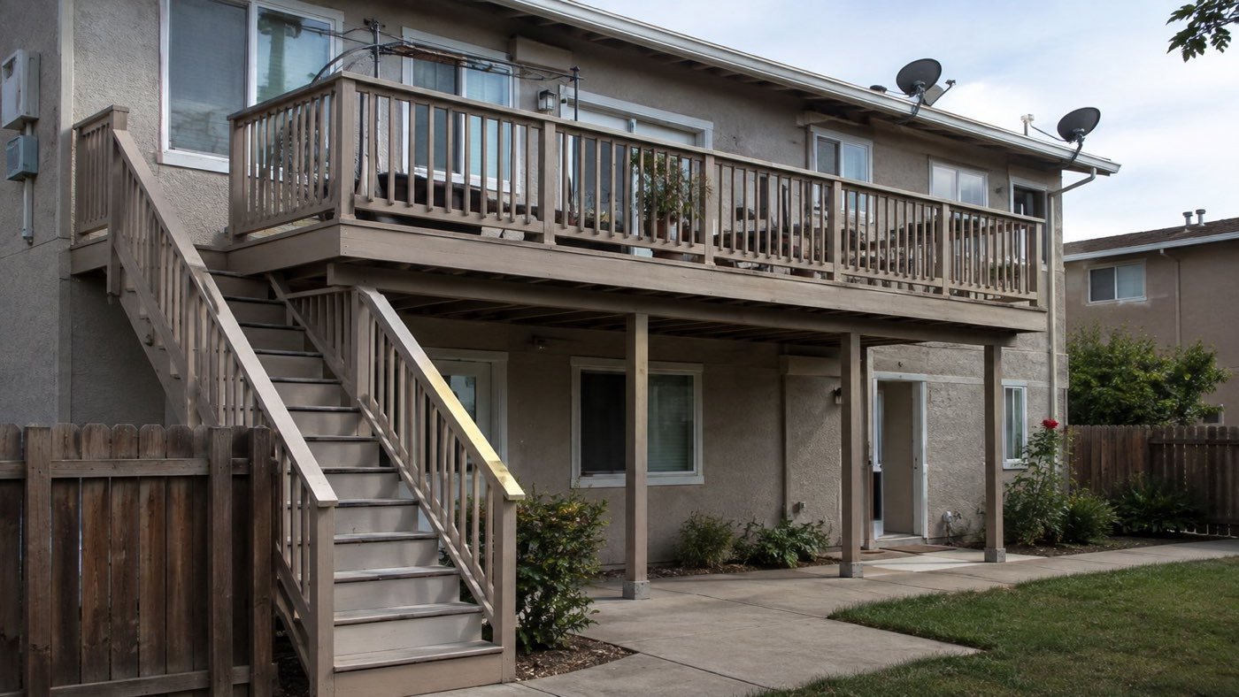Aging second-floor wood deck and exterior stairway on a California multifamily building