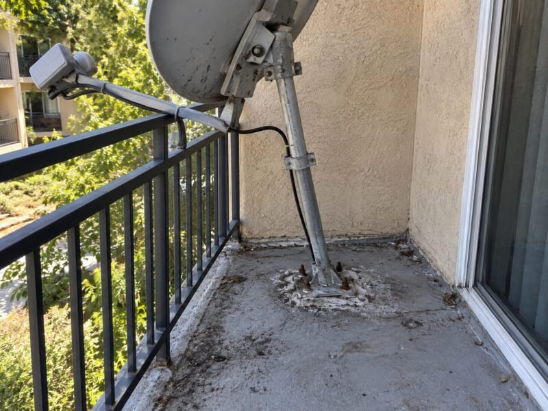 Satellite dish mount bolted directly through a balcony waterproofing membrane in San Jose