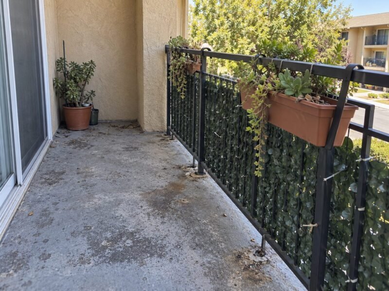 Planter hooks and privacy screen anchors punched through a balcony deck coating