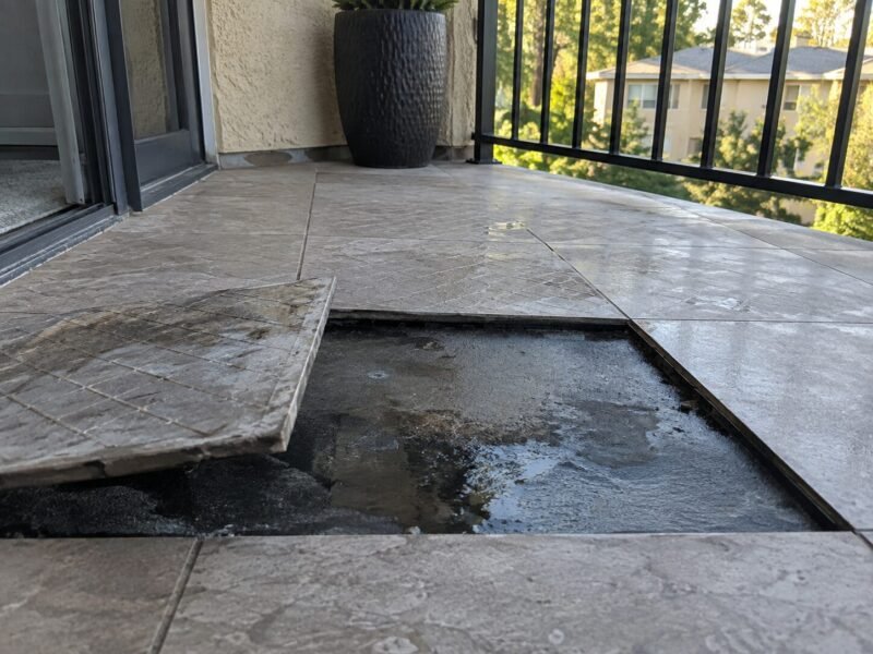 Owner-installed tile lifted from a condominium balcony revealing trapped water beneath the coating