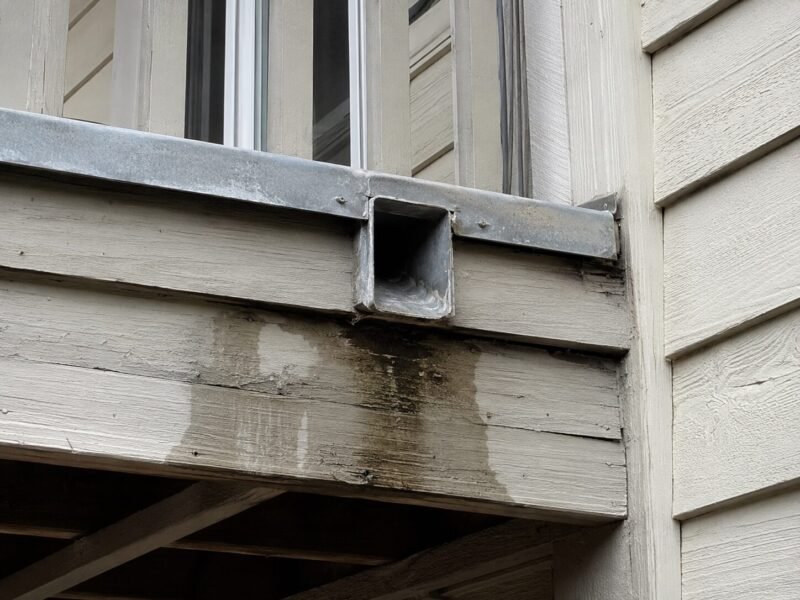 Scupper discharging water directly onto balcony framing at a Woodland townhome