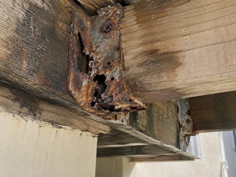Corroded joist hanger with section loss beneath a Hayward apartment balcony