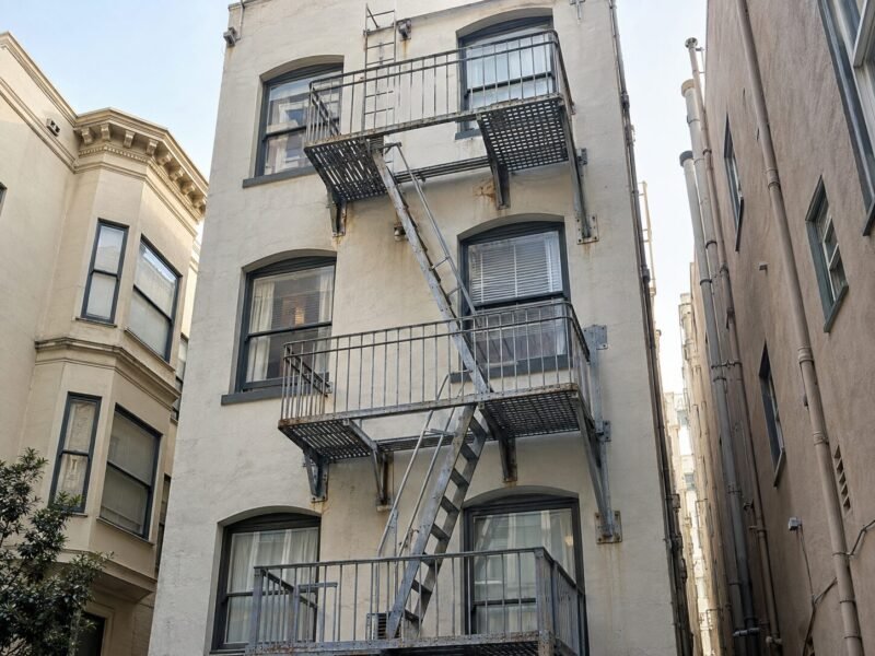 Riveted steel fire escape on a North Beach hotel being assessed during a Section 604 inspection in San Francisco